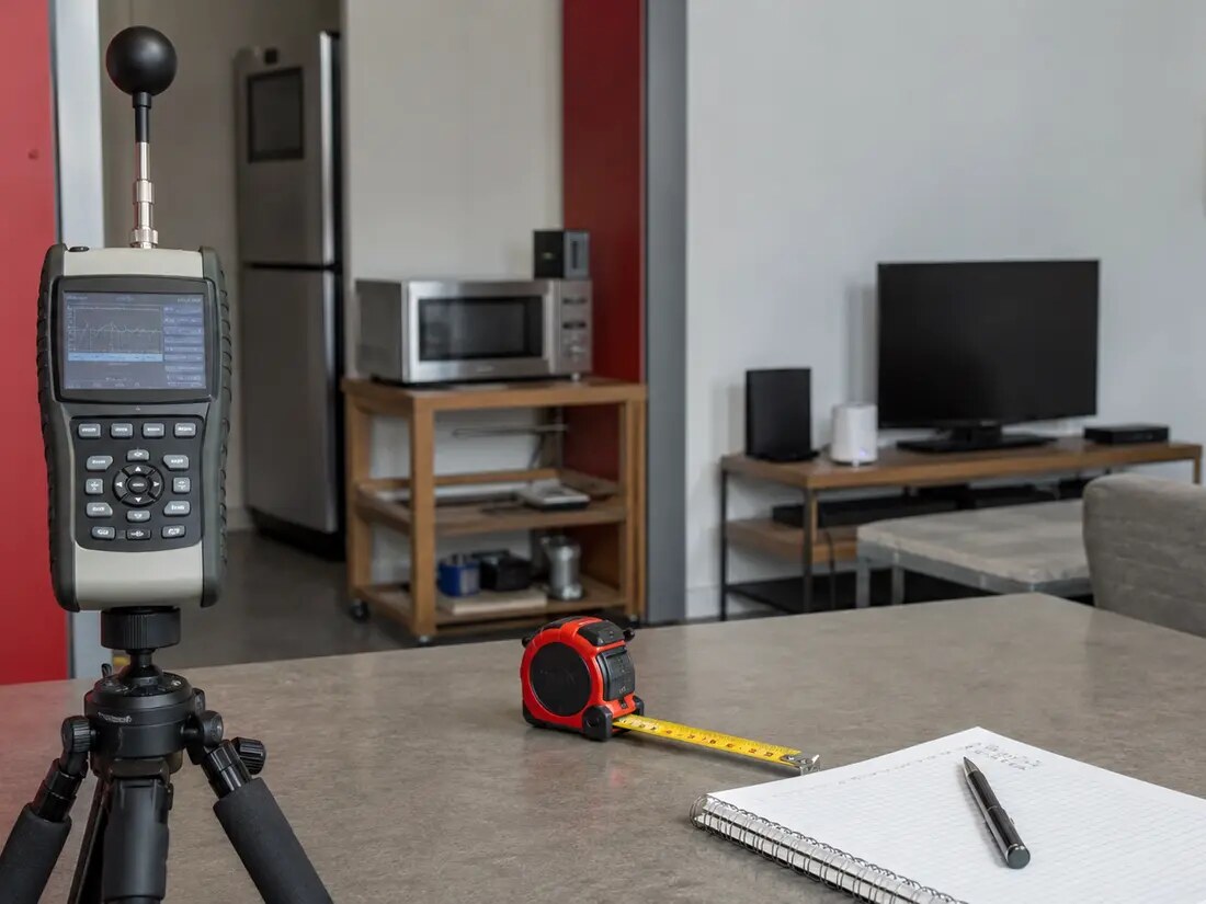 A closer documentary view of a radiofrequency meter on a tripod in a controlled household measurement setup.