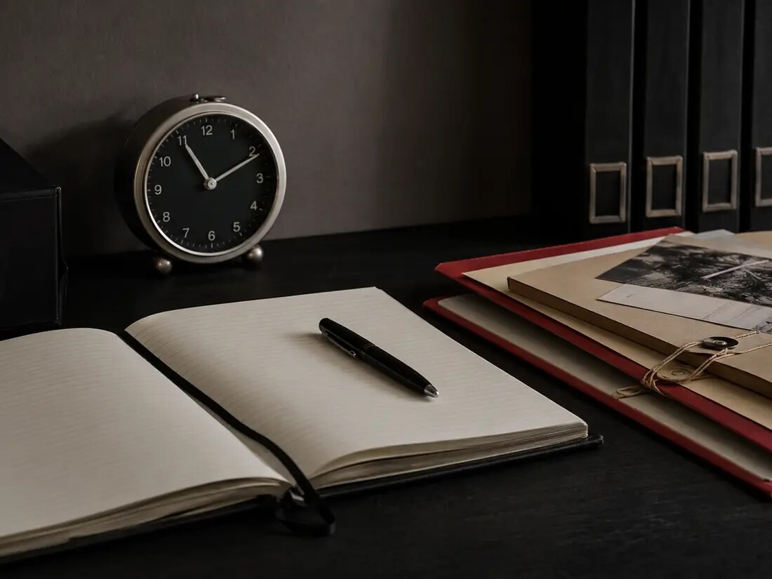 A closer documentary view of an incident log, clock, pen, and evidence folders.